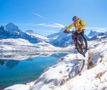 Person jumping on mountain bike in snowy trails Person jumping on mountain bike in snowy trails