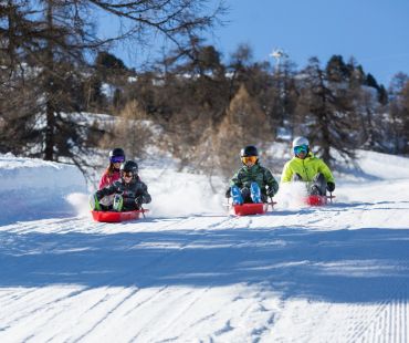 People enjoying sledding down snowy trails People enjoying sledding down snowy trails