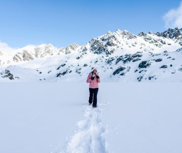Person wearing snowshoes hiking through deep snow Person wearing snowshoes hiking through deep snow